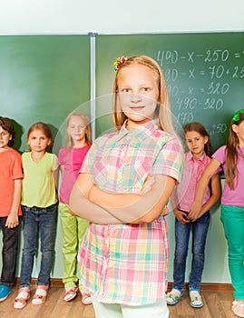 Smiling girl with arms crossed near chalkboard