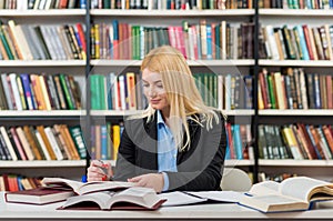 Smiling girl with blonde hair sitting at a desk in the lib