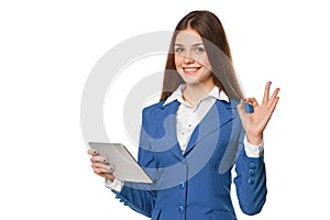 Smiling girl in blue suit using tablet showing okay sign. Woman with tablet pc, isolated on white background