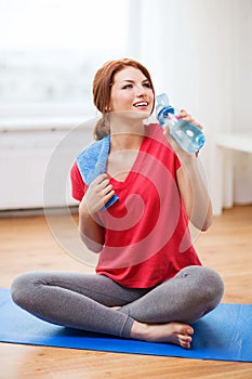 Smiling girl with bottle of water after exercising