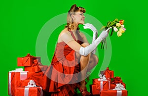 Smiling girl with bouquet of flowers and present. Spring flowers and gift box. Beautiful woman in red dress with retro
