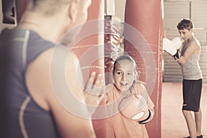 Smiling girl at boxing workout at gym on punching bag