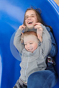 Smiling girl and boy having fun on children`s slide
