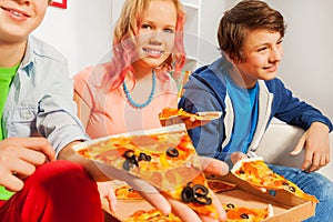 Smiling girl and boys holding pizza pieces at home