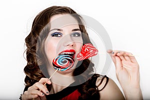 Smiling girl with braces holding heart candy posing on a white background