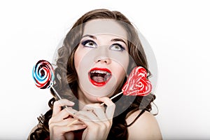 Smiling girl with braces holding heart candy posing on a white background