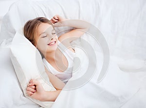 Smiling girl child waking up in bed at home