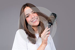 Smiling girl combing hair. Beautiful young woman holding comb straightened hair. Attractive smiling woman portrait with