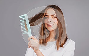 Smiling girl combing hair. Beautiful young woman holding comb straightened hair. Attractive smiling woman portrait with