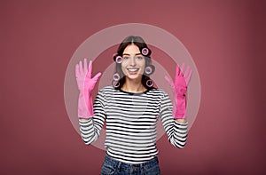 Smiling girl in curlers and rubber gloves for cleaning