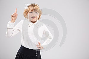 A smiling girl demands attention with a raised finger.