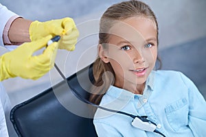 Smiling girl and doctors hands with special earphone