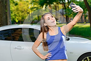 Smiling girl doing selfie on background of car