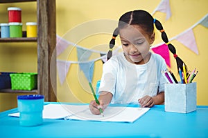 Smiling girl drawing in her colouring book