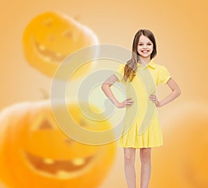 Smiling girl in dress over pumpkins background