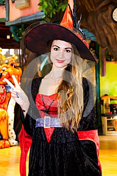 Smiling girl dressed as a Halloween witch showing victory gesture