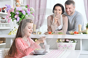 Smiling girl eating at kitchen