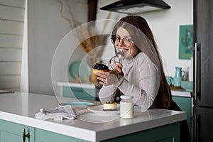 Smiling girl eats a sweet dessert at the kitchen. Caloric carbohydrates in food
