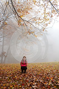 Smiling girl enjoying day in foggy autumn forest.