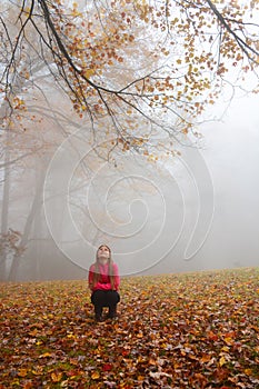 Smiling girl enjoying day in foggy autumn forest.