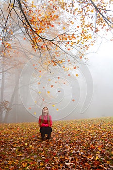 Smiling girl enjoying day in foggy autumn forest.