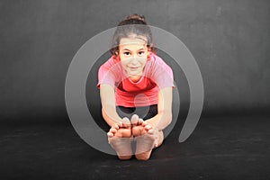 Smiling girl exercising yoga - seated forward fold