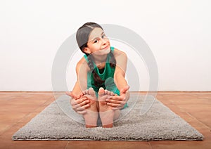 Smiling girl exercising yoga - seated forward fold