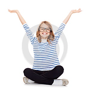 Smiling girl in eyeglasses sitting on floor