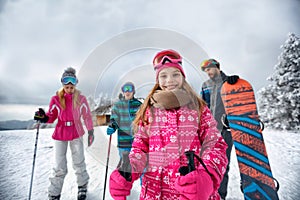 Smiling girl with family on ski slope on vacation in mountain