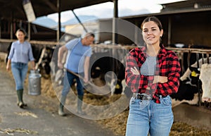 Smiling girl farmer posing in outdoor cowshed at livestock farm