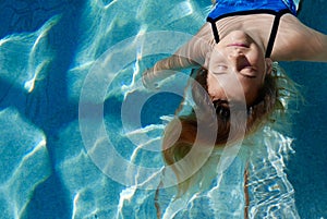 Smiling girl floating in the pool with negative space