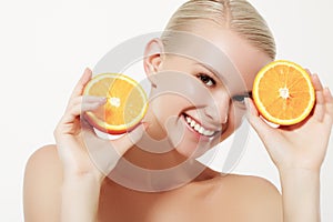 Smiling girl with fresh fruits. Beauty model takes juicy oranges. Joyful girl with freckles. The concept of a healthy