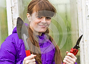 Smiling girl with garden tools in hand