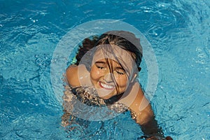 Smiling girl getting out of the water in the pool.