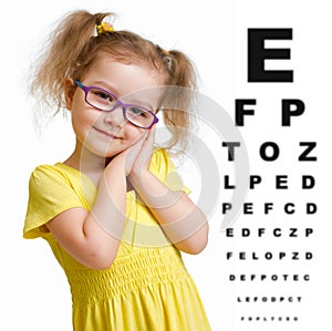 Smiling girl in glasses with eye chart isolated