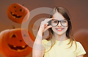 Smiling girl in glasses over pumpkins background