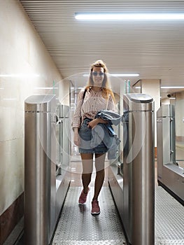 Smiling girl goes through the iron turnstile at the railway station