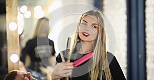 Smiling girl hairdresser holding different combs, close-up