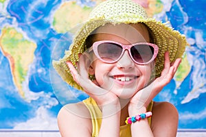Smiling girl in a hat and sunglasses on the background of the world map