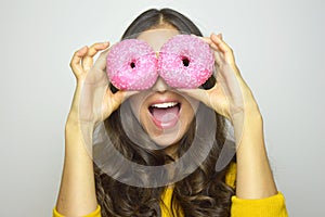 Smiling girl having fun with sweets isolated on gray background. Attractive young woman with long hair posing with doughnuts