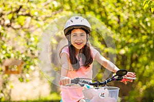 Smiling girl in helmet ride on the pink girly bike