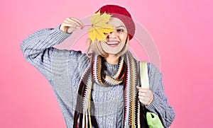 Smiling girl hides eye by yellow maple leaf. Woman in warm clothes with shopping bag. Season sale.