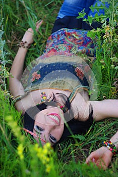 Smiling girl hippie lying in the grass and flowers. Boho style,