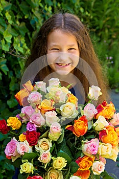 Smiling girl holding big bouquet of roses in hands.