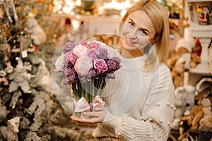 Smiling girl holding a bouquet of tender pink and purple color flowers with green stalks