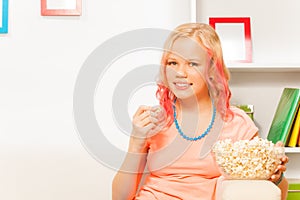 Smiling girl holding bowl with popcorn at home