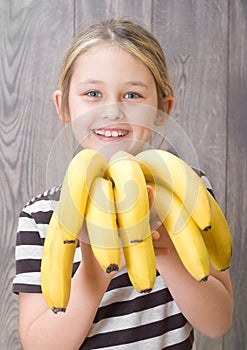 Smiling girl holding a bunch of bananas