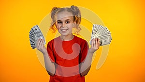 Smiling girl holding bunches of dollar cash and looking to camera, motivation