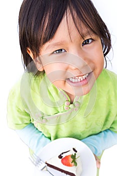 Smiling girl holding chocolate cake on white plate. Happy face.