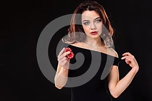 Smiling girl holding a gambling chips in her hands on black background. Copy space